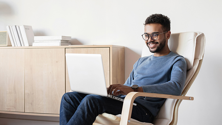 a man sitting and smiling with a laptop on his lap