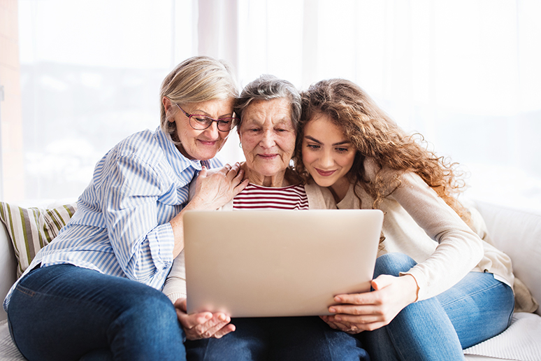 A teenage girl, mother and grandmother with laptop at home