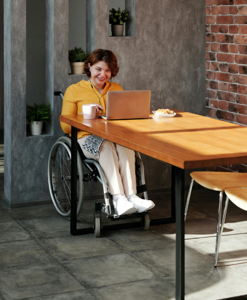 A woman on a wheelchair smiling and working at a desk