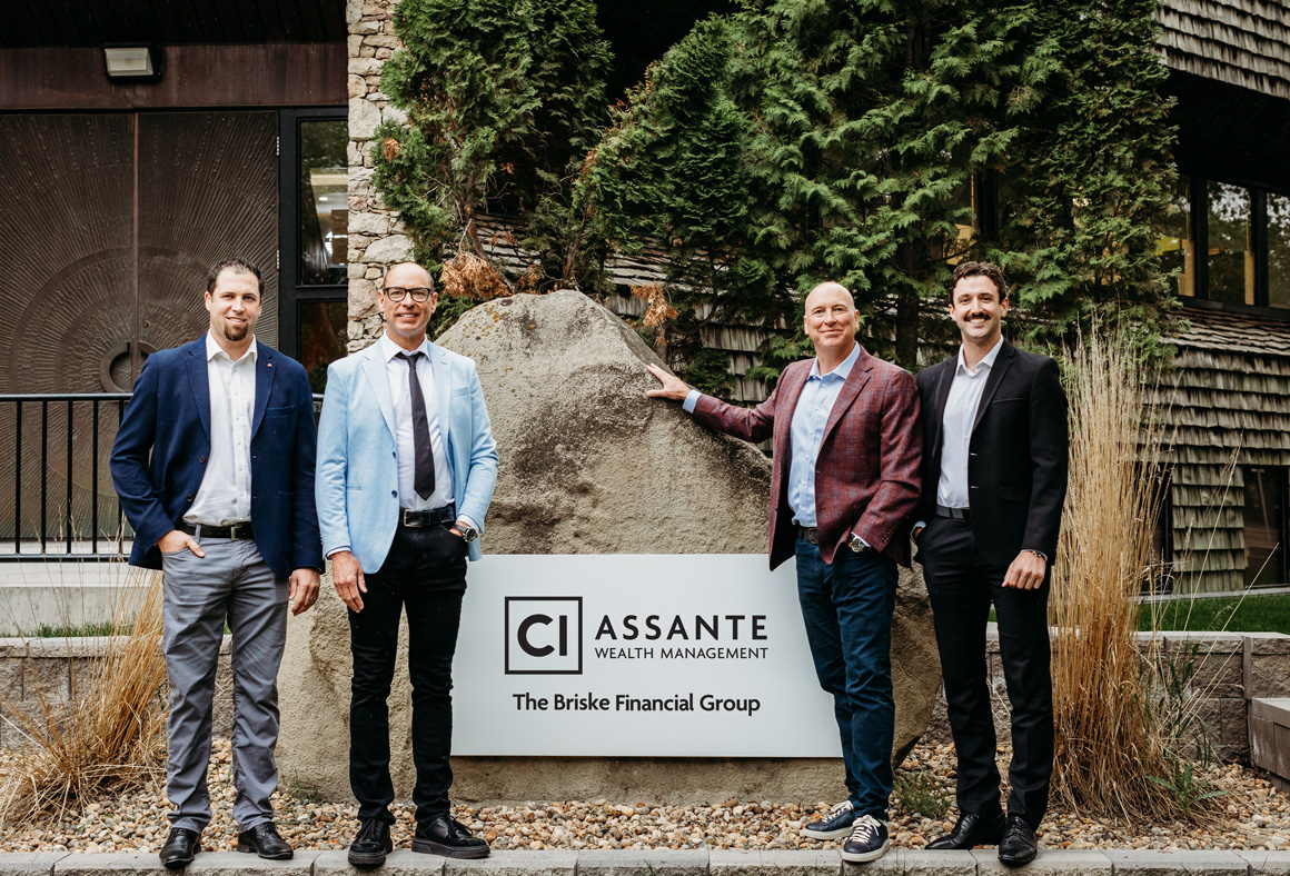 Four men in business suits smiling and standing in front of a rock that reads "CI Assante Wealth Management The Briske Financial Group"